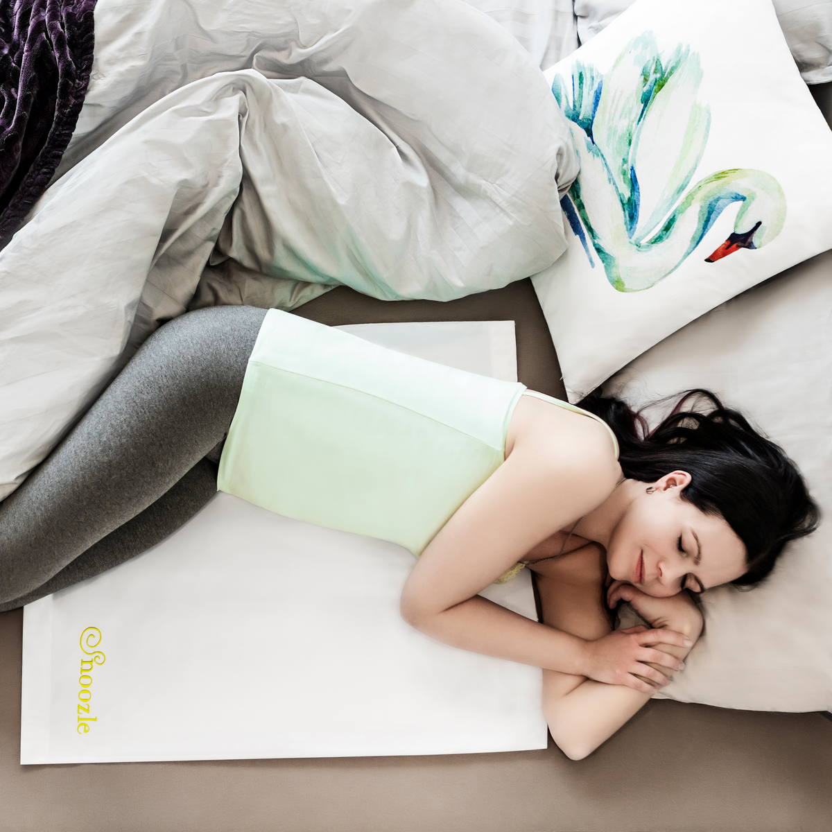 Woman resting on a bed with the white Snoozle Slide Sheet